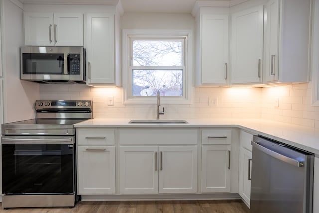 kitchen featuring white cabinets, backsplash, stainless steel appliances, and sink