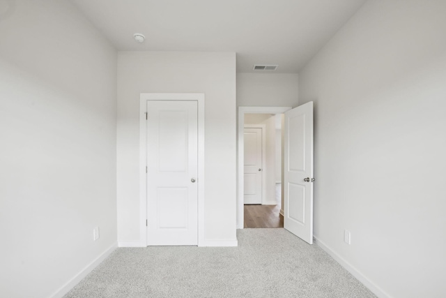 unfurnished bedroom with baseboards, visible vents, and light colored carpet