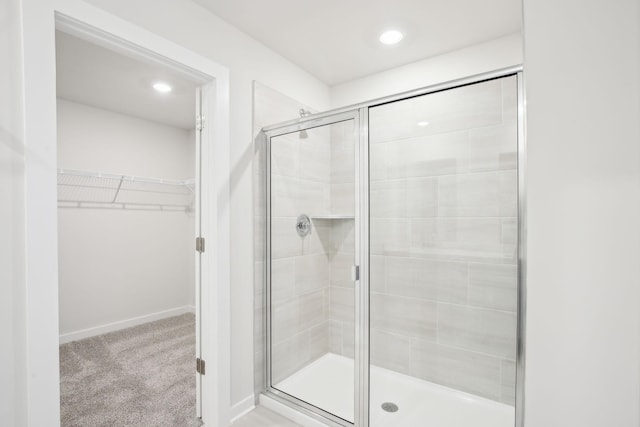 full bathroom with a shower stall, a spacious closet, and baseboards