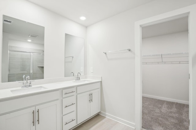 bathroom with a walk in closet, visible vents, a sink, and a shower stall