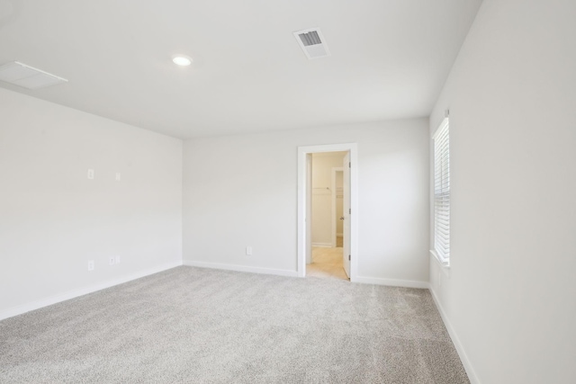 spare room with recessed lighting, visible vents, light carpet, and baseboards