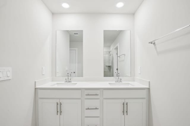 full bathroom with a stall shower, a sink, and double vanity