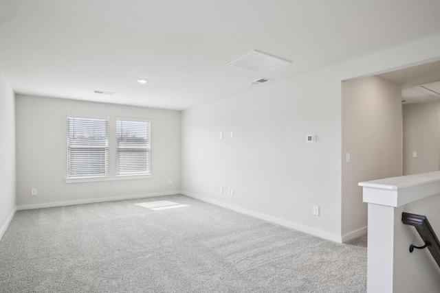 empty room featuring light carpet, visible vents, and baseboards