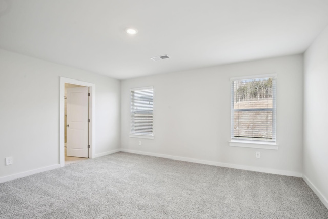 empty room featuring baseboards, visible vents, and light colored carpet