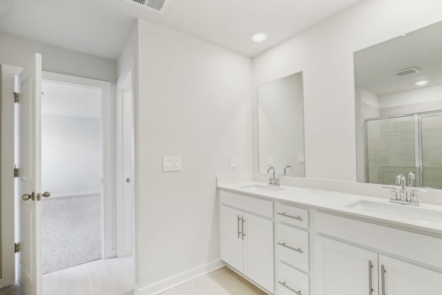 bathroom featuring double vanity, a shower stall, visible vents, and a sink