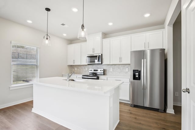 kitchen with stainless steel appliances, an island with sink, a sink, and white cabinetry