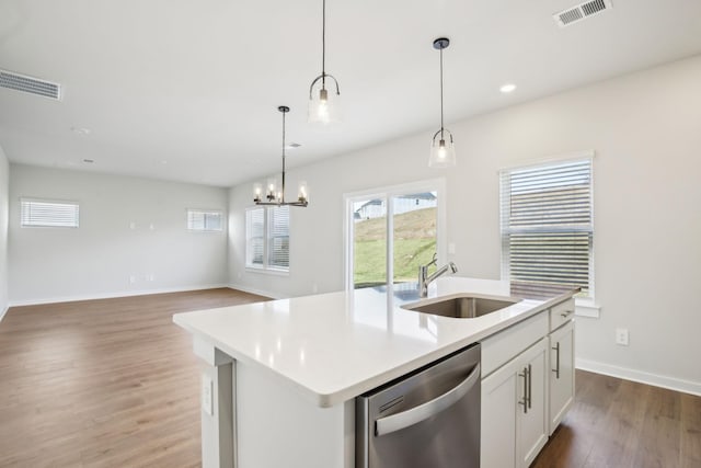 kitchen featuring visible vents, hanging light fixtures, a kitchen island with sink, stainless steel dishwasher, and a sink