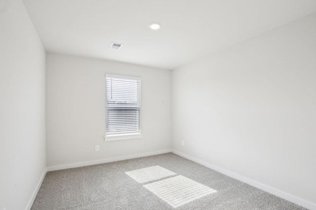 empty room featuring carpet floors, visible vents, and baseboards