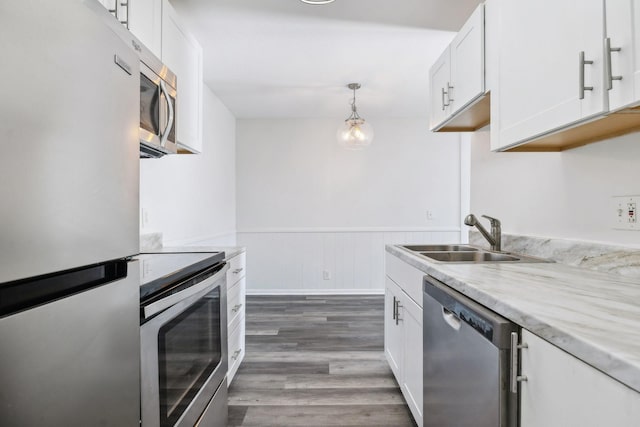 kitchen featuring stainless steel appliances, sink, white cabinets, dark hardwood / wood-style floors, and hanging light fixtures