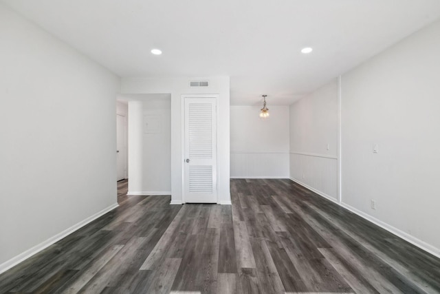 empty room featuring dark hardwood / wood-style flooring and a chandelier