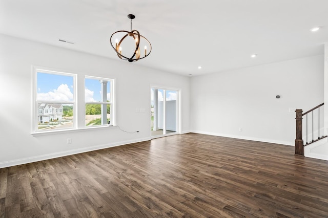 unfurnished living room featuring dark wood-type flooring and a chandelier