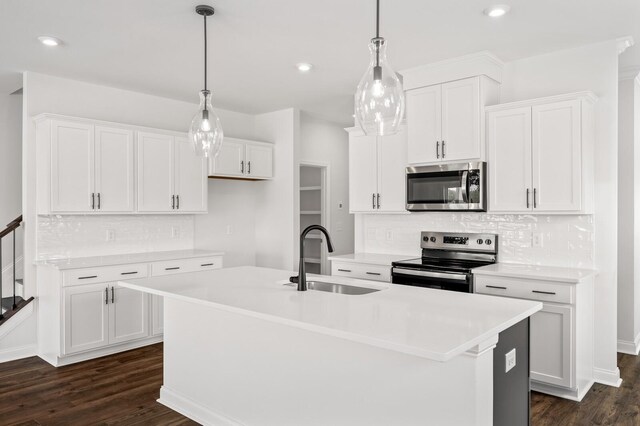 kitchen with white cabinets, sink, stainless steel appliances, and a kitchen island with sink