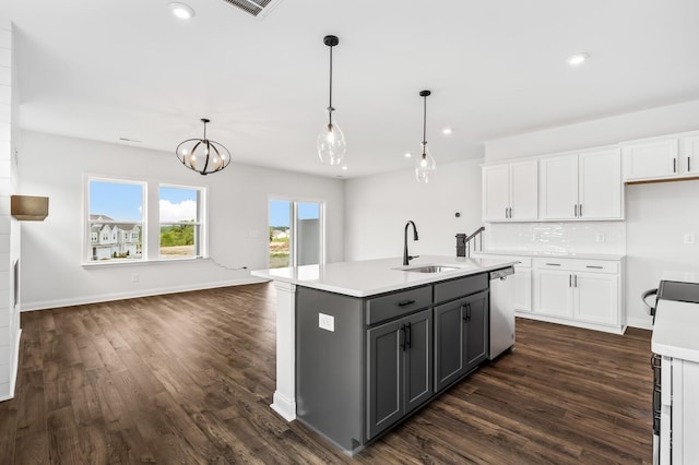 kitchen with white cabinets, sink, hanging light fixtures, stainless steel dishwasher, and an island with sink