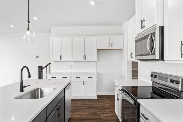 kitchen with sink, hanging light fixtures, stainless steel appliances, dark hardwood / wood-style floors, and white cabinets