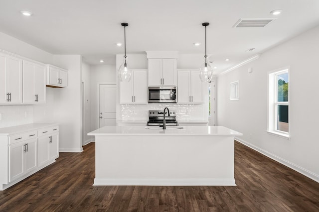 kitchen with a center island with sink, white cabinets, and stainless steel appliances