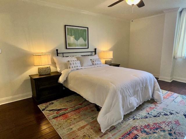 bedroom with ceiling fan, crown molding, and dark wood-type flooring