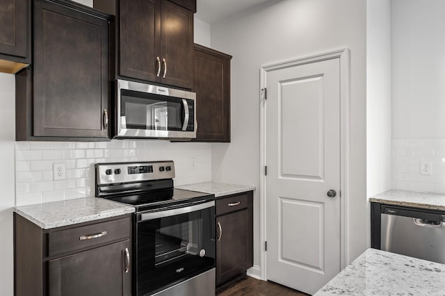 kitchen with light stone countertops, stainless steel appliances, tasteful backsplash, and dark hardwood / wood-style floors