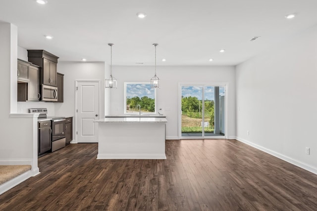 kitchen featuring stainless steel appliances, dark wood-type flooring, sink, decorative light fixtures, and a center island