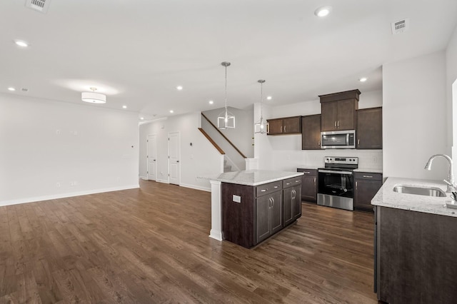 kitchen with sink, dark hardwood / wood-style floors, appliances with stainless steel finishes, decorative light fixtures, and dark brown cabinetry