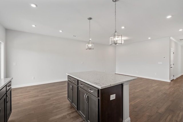 kitchen featuring light stone counters, a center island, dark hardwood / wood-style floors, and decorative light fixtures