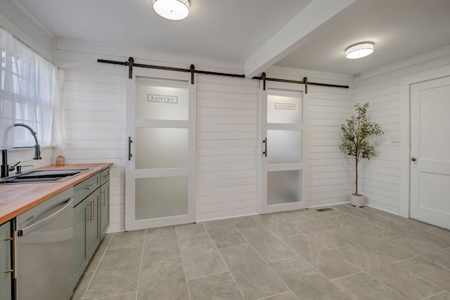 kitchen with sink, stainless steel dishwasher, butcher block countertops, and a barn door