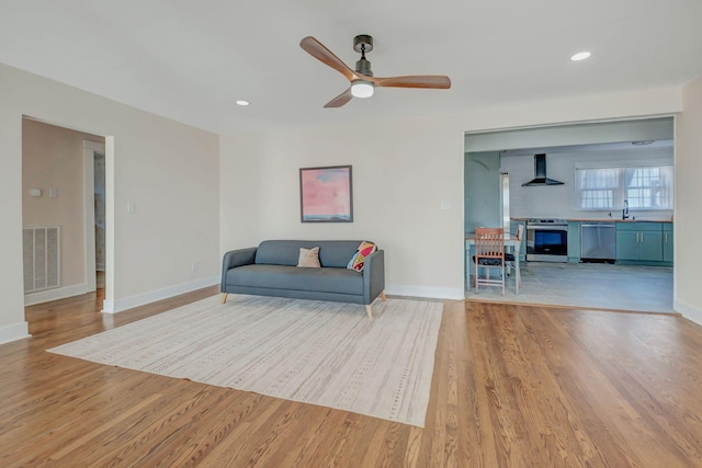 living area with light hardwood / wood-style floors, sink, and ceiling fan