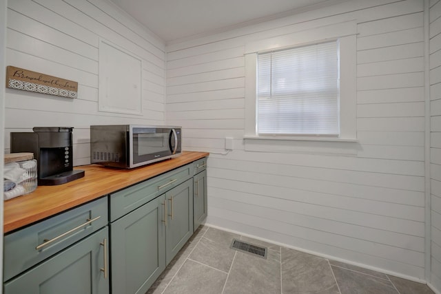 interior space with wooden walls, light tile patterned floors, and wooden counters