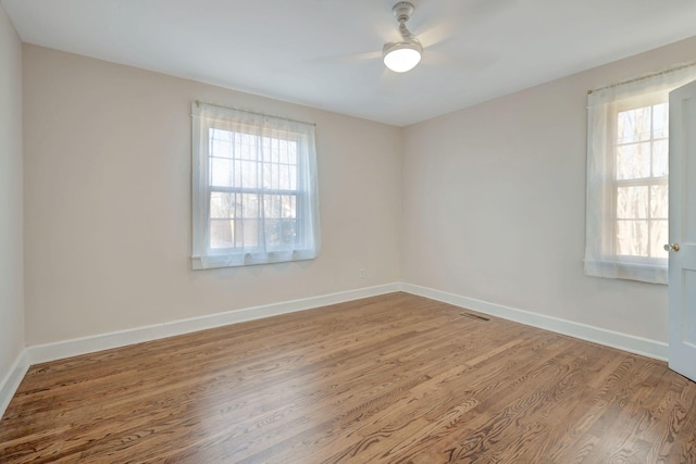 empty room featuring hardwood / wood-style flooring, a wealth of natural light, and ceiling fan