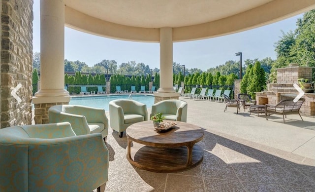 view of patio featuring a community pool and an outdoor stone fireplace