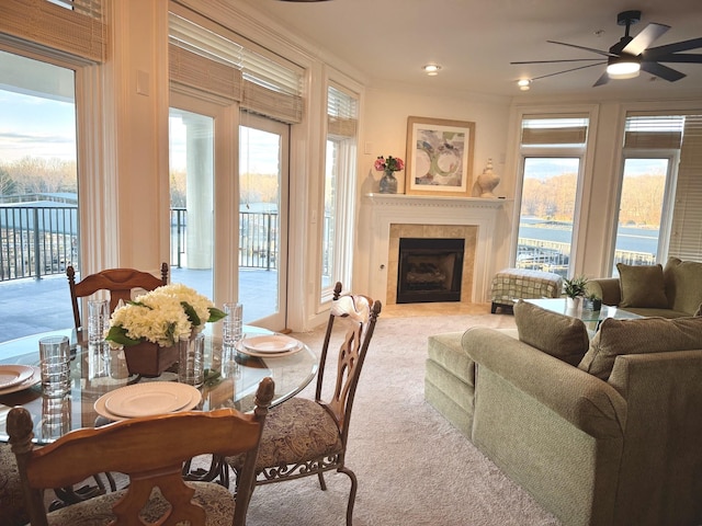 dining room featuring a tiled fireplace, ceiling fan, crown molding, and carpet