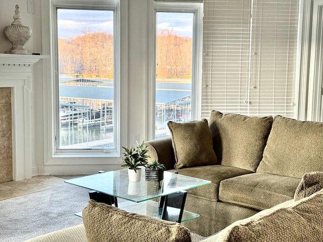 living room with carpet flooring, a tile fireplace, and a water view