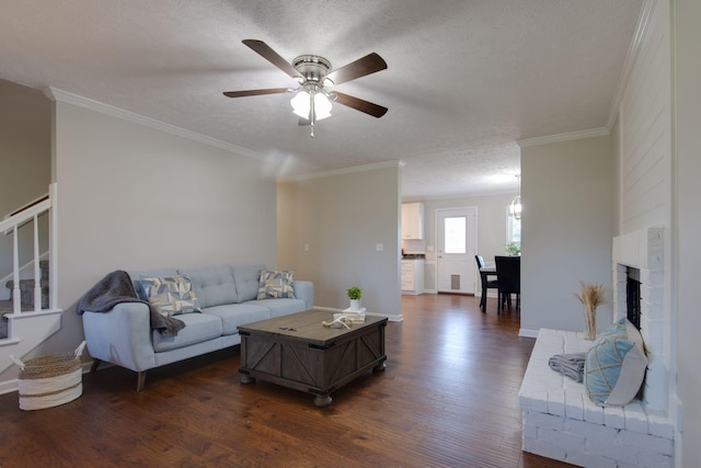 living room featuring a brick fireplace, ceiling fan, ornamental molding, a textured ceiling, and dark hardwood / wood-style flooring