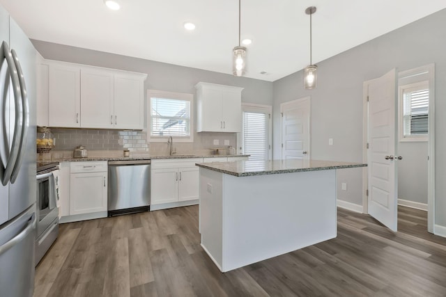 kitchen with stone countertops, sink, decorative light fixtures, white cabinetry, and stainless steel appliances