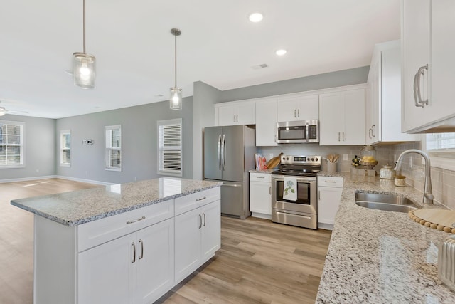 kitchen featuring pendant lighting, white cabinetry, sink, and appliances with stainless steel finishes