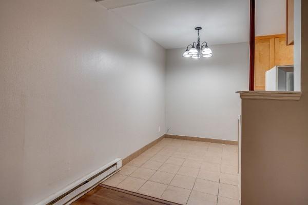 spare room featuring a notable chandelier and a baseboard radiator