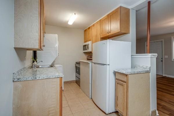 kitchen featuring light brown cabinets, white appliances, and sink