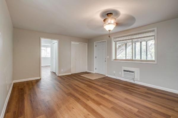 spare room featuring a wall mounted air conditioner, ceiling fan, and hardwood / wood-style floors