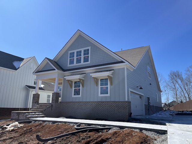 view of front of property with board and batten siding, brick siding, and a garage