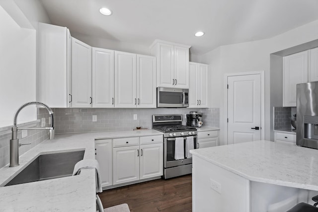 kitchen featuring white cabinets, stainless steel appliances, tasteful backsplash, and sink