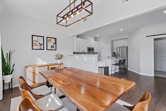 dining room featuring a barn door and dark wood-type flooring