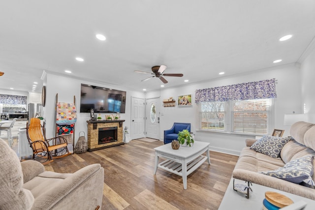 living room featuring a stone fireplace, ceiling fan, a healthy amount of sunlight, and ornamental molding