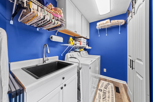 washroom with cabinets, light hardwood / wood-style floors, washer and clothes dryer, and sink