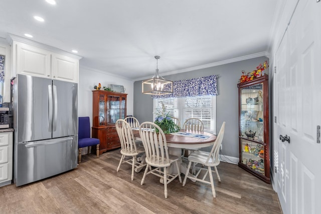 dining area with ornamental molding, light hardwood / wood-style flooring, and a notable chandelier