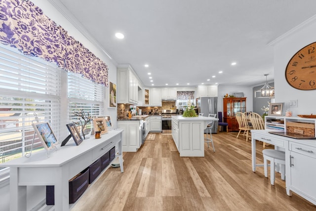 kitchen featuring pendant lighting, a center island, white cabinets, tasteful backsplash, and a kitchen bar