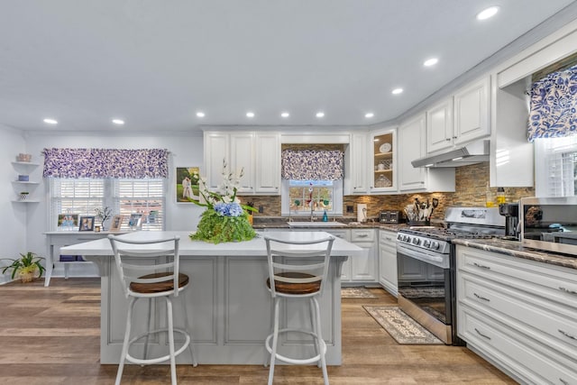 kitchen with gas range, white cabinets, a kitchen bar, a kitchen island, and light wood-type flooring