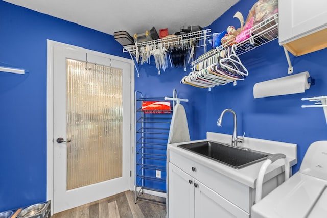 washroom with cabinets, wood-type flooring, separate washer and dryer, and sink