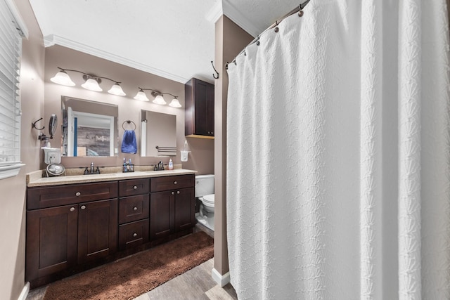 bathroom with vanity, toilet, wood-type flooring, and crown molding