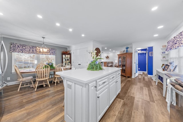 kitchen with a center island, white cabinets, crown molding, hanging light fixtures, and range