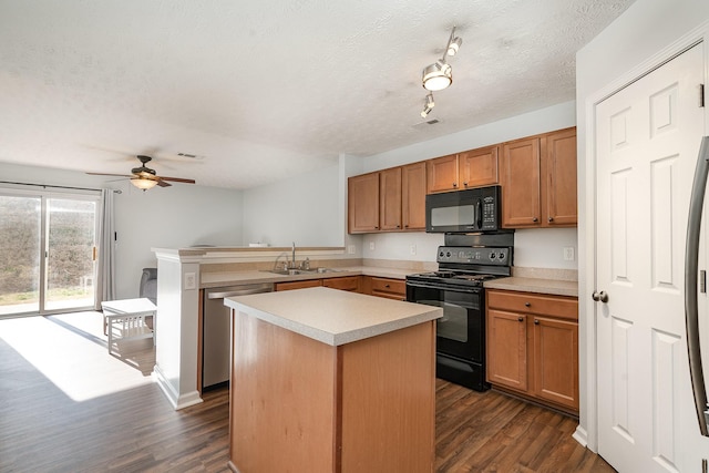 kitchen with sink, a center island, dark hardwood / wood-style floors, a textured ceiling, and black appliances