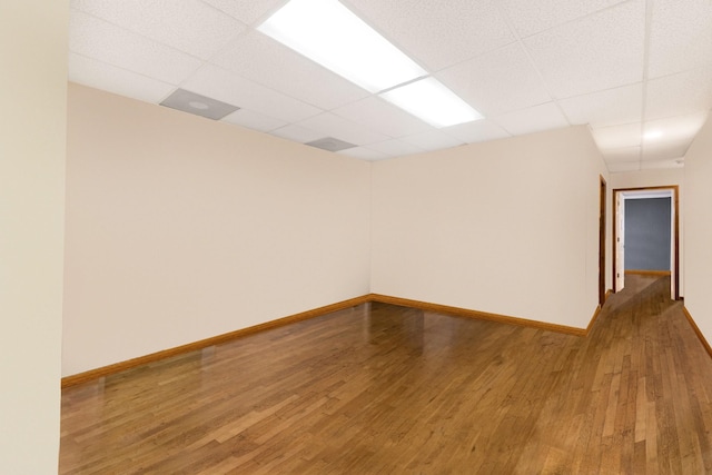 unfurnished room with a drop ceiling and wood-type flooring